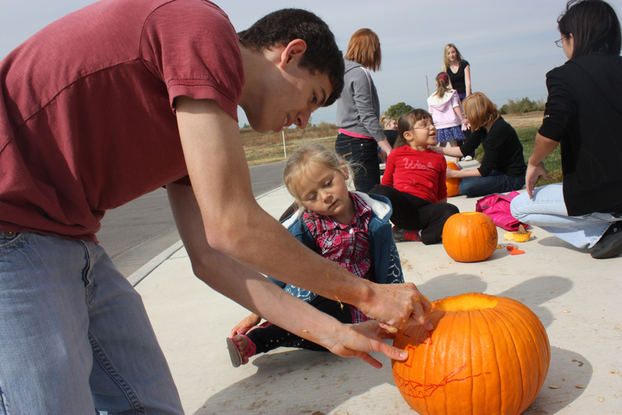 Aaron Schmidt, 12, carves a pumpkin with a student from ECC on Oct. 27. Students from Mikel Tinichs Honors Biology enjoyed the opportunity to work with the younger kids. Photo by A. Esser