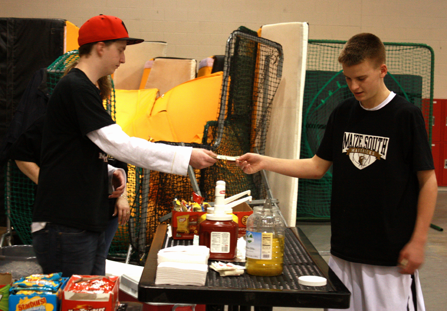 Bowler Alec Patterson, 11, takes a hungry Spencer Bruner’s money after he ordered a hot dog on Dec. 6. Bruner was there to watch varsity take on Salina Central. The boys lost 61-39. Photo by A. Esser