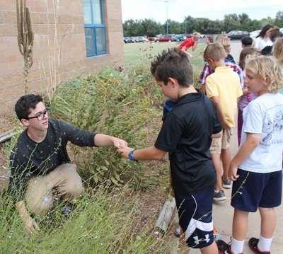Junior Stylan Roberts shows a Pray-Woodman 3rd grader the garden in Jay Super's Botany class.