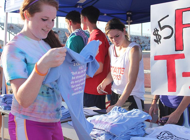 Junior Sarah Slack reads a t-shirt at the Fellowship of Christian Athletes booth at the extravaganza Aug. 30. Also pictured senior Whitney Lucas. Photo by Kalee Betzen.