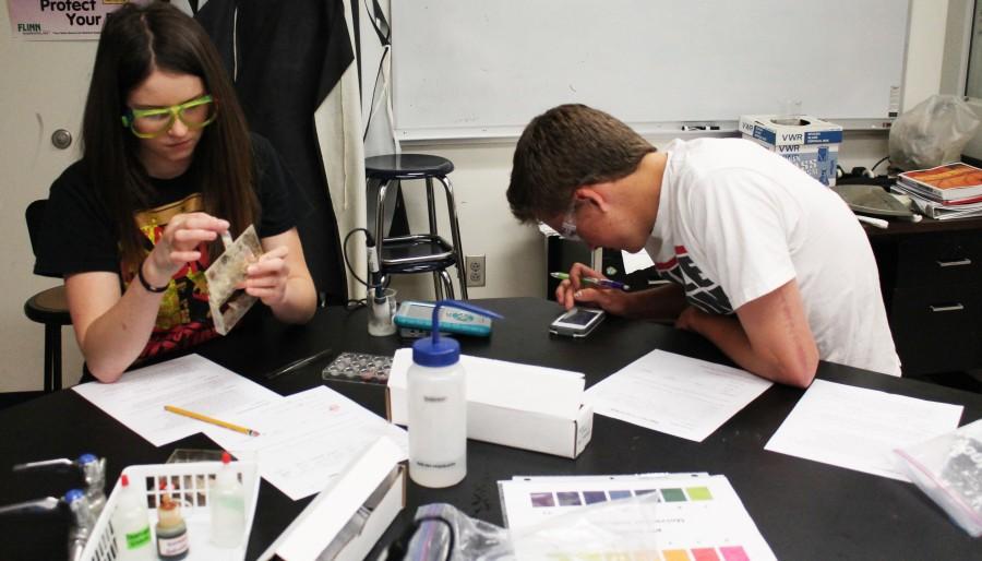 Junior Emily Scheuffele tests the PH balance of common solutions while her chemistry partner, Sophomore Harrison Shively, plays a game on his IPhone.