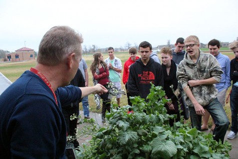 Horticulture teacher Jay Super is outside with his students teaching them the differences between plants.  All of the plants in their garden, were planted by students, to provide a hands-on experience.