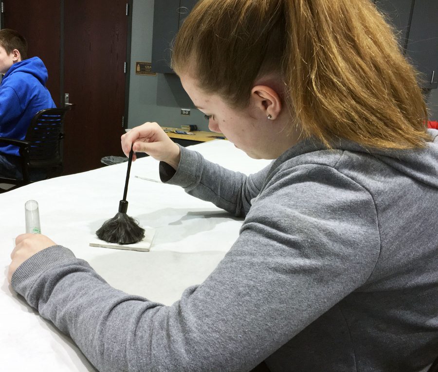 Camie Shivers, 10, dusts for latent fingerprints during the field trip on Feb. 22. She dusted to be able to see her fingerprints left on a tile.  Photo by L. Chavez.