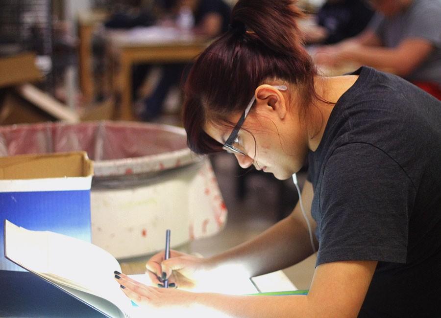 Maica Parga outlines her perspective nametag on a tracing table in Amanda Goschs Drawing II class.