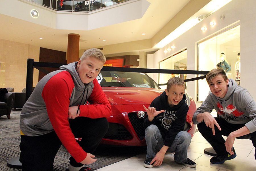 Caleb Dillon, Gavin Matthews, and Bryce Nelson pose beside one of the cars at the mall. Today during second through the beginning of fourth block,  some of the Friendship Club members went on a field trip to the East mall. Photo by Allison Franco.