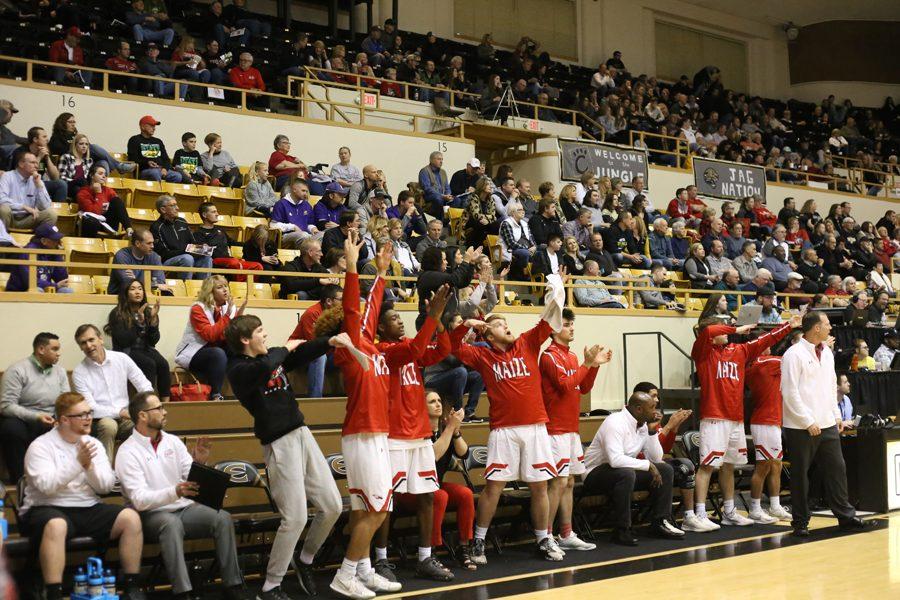 Basketball players on the bench cheer after a three-pointer was made in the first half.
