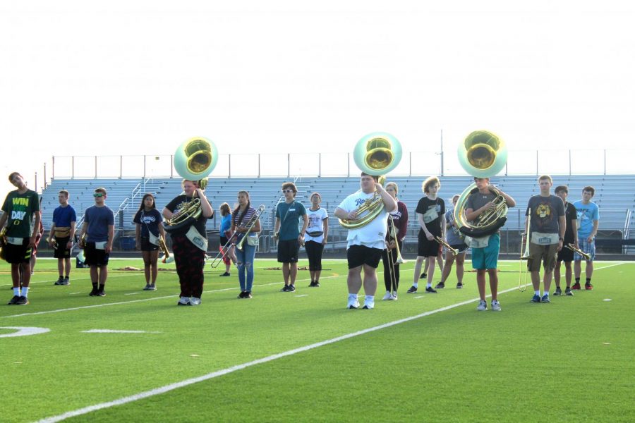 Band members gather in the middle of the football field to practice their team marching.