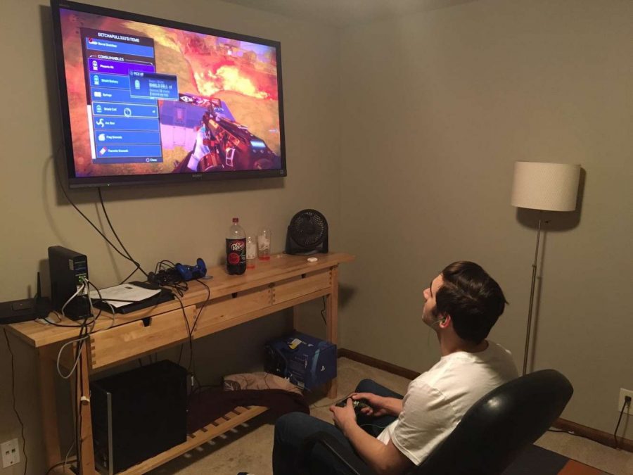 Junior Ralph Corriveau sits in his gaming chair while playing Apex Legends with his friends. Corriveau  enjoys Cheeze-Its and other salty snacks when he games.