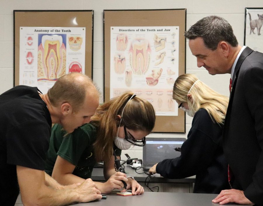 Visiting a Health Science classroom in  September 2019, Dr. Chad Higgins examines instructor Rob Archibald as he shows the proper technique on drilling and removing cavities. This unit gives exposure to the dentistry field with hands on activities.