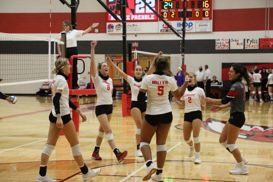 The varsity volleyball team celebrates after scoring. The team won this match. 