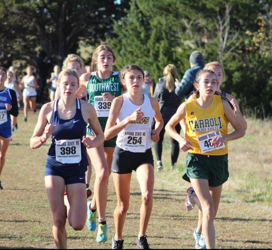 Running alongside the other cross country runners from around Kansas, Alexa Rios (12), runs a fast as attemps to get ahead of her competition.  Her efforts, combined with the rest of the team, resulted in a 1:39:55 combined total time, twenty seconds less than runners up, Bishop Carroll.