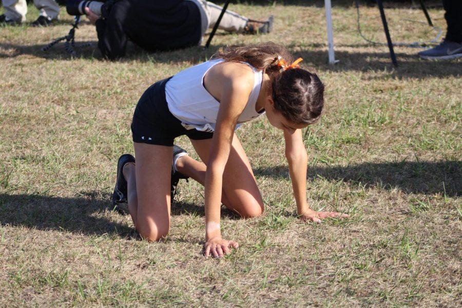 After finishing the four mile course, Alexa Rios (12) collapses on the grass of exhaustion.  She finished the race with an average speed of 6:12 a mile to grab 5th place overall in the girls 5A division.