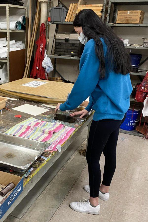Senior Mary Rozner spreads out paint on a pane of glass for printmaking. After layering the paint, the glass pane is placed on a piece of paper and the print is transferred.