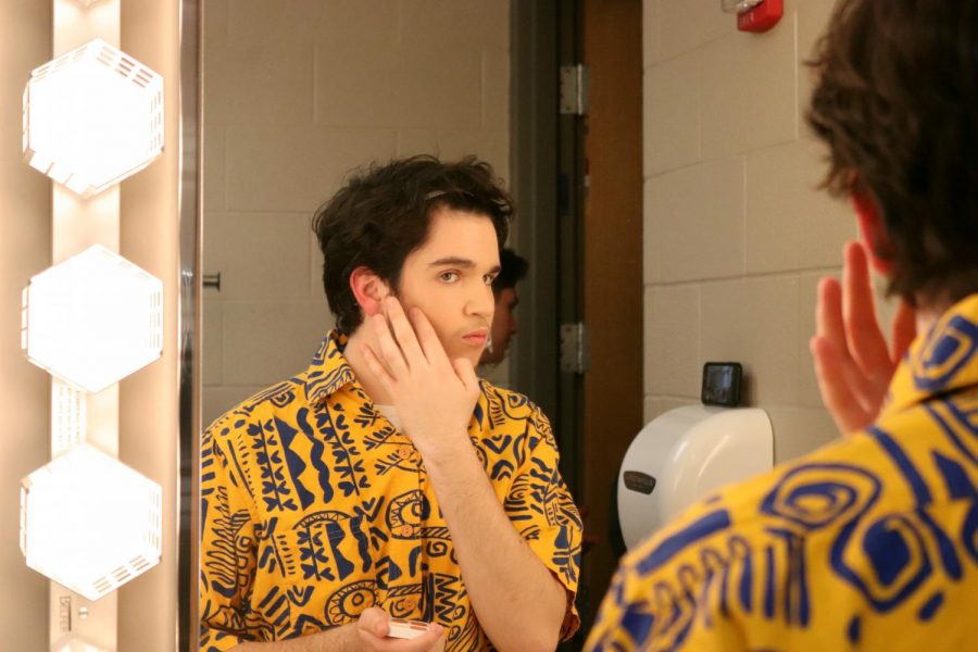 Before the rehearsal, Junior John Waren peers in the mirror and gets into his first character of the production. Waren also played two other roles in Leaving Iowa. 
