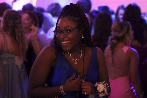 Senior Kiara Colbert laughs as she talks to her friends and enjoys her time at prom. Colbert wore a dark blue dress with her hair in a high ponytail and matching heels and jewelry.