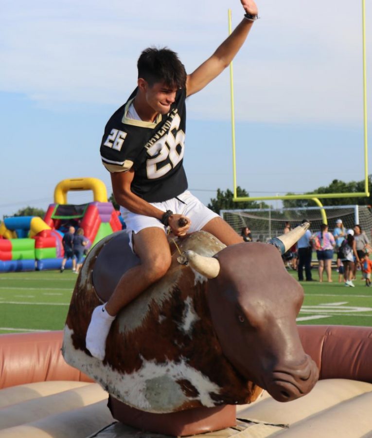 Sophomore Robert Albert holds his balance on the mechanical bull at the school carnival. This was a popular ride among the group of students from the Maize South district. 