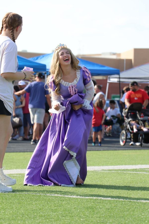While walking around encouraging kids to get a photo with their favorite characters, senior Sarah McKay, who is dressed as Rapunzel,  shares a laugh with a classmate. 