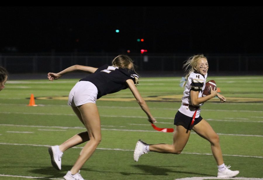 Junior Ava Miller runs the ball as senior defender Avery Lowe, rushes in to take Millers flag. Maize South juniors defeated Maize South seniors 18-12 in the annual homecoming powder puff game. 
