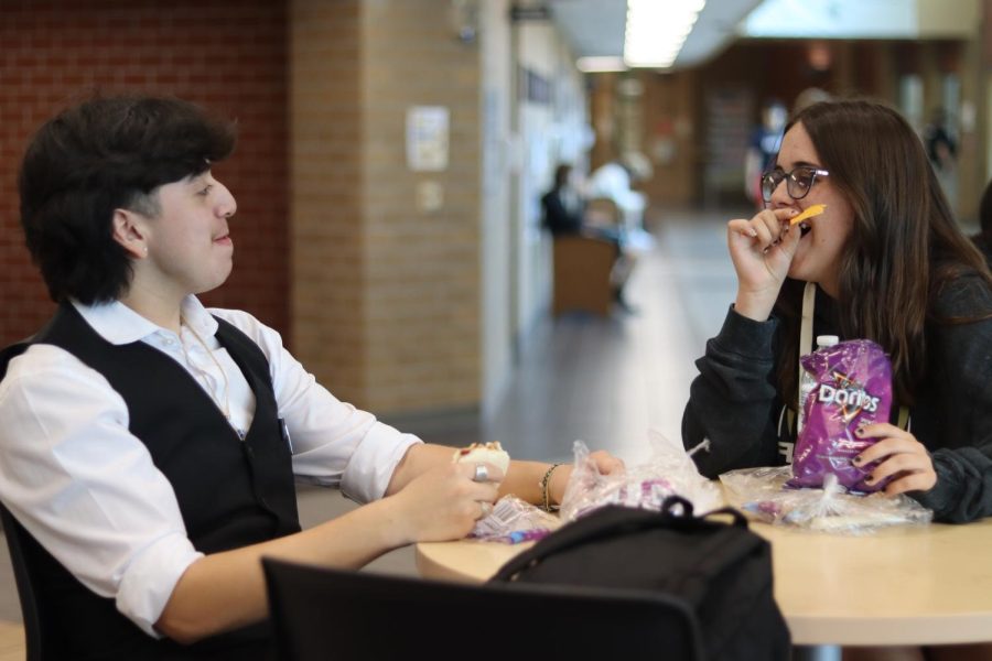 Dacey Willson (11) and Eli Cruz-Quintero (11) eat lunch in the crowded lunch room at Maize South. While having to deal with changes in their daily routines at school, seeing their friends at lunch remains consistent. 
