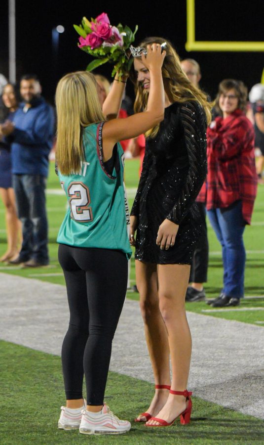 Senior Maggie Salsbury receives her homecoming queen crown during halftime from Maize High stuco member Ella Strobel. Salsbury was one of five homecoming queen candidates.