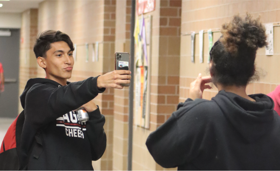Senior Damian Cabrales takes his daily BeReal with his friends in the hallway. They pose to have the best picture possible. I get to show off where I am at that specific time, and I get to see where everyone else is at, Cabrales said.
