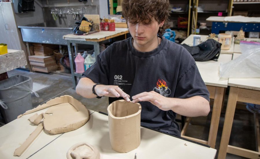 Junior Kyler Sianis works on his pinch pot in Mrs. Carlsons ceramics class. The projects have been pretty fun so far. I feel like they get my creative juices flowing, said Sianis.