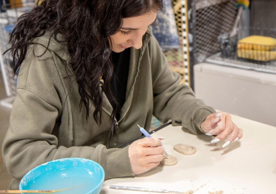 Senior Savannah Kniep uses a stylus to add extra details to her clay ear.