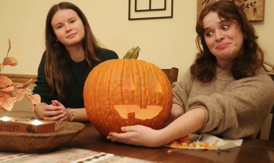two girls carve a pumpkin