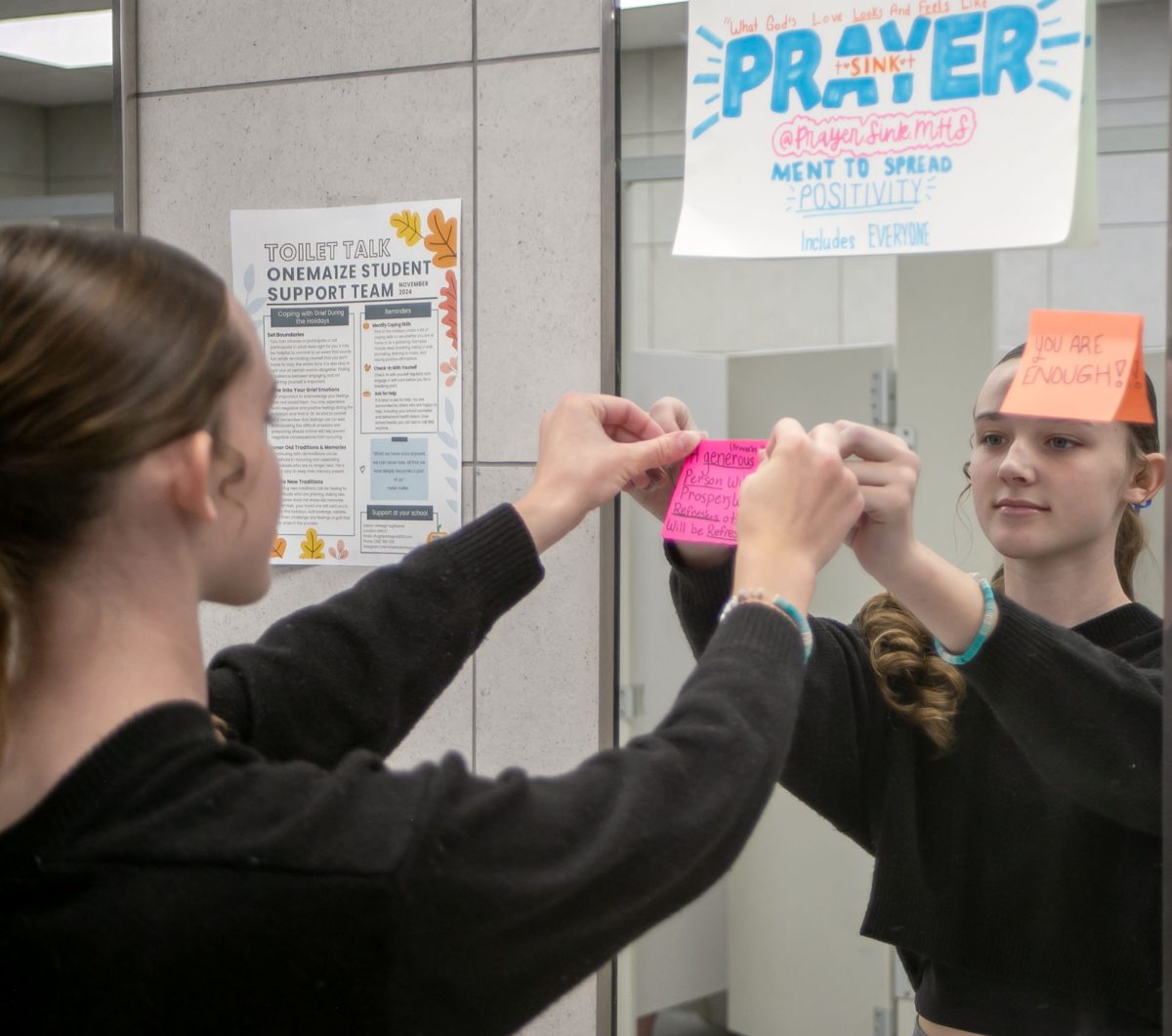 Taylor Dill puts up a prayer sink in the girls’ bathroom at MHS. Dill started the prayer sink initiative in 2023.